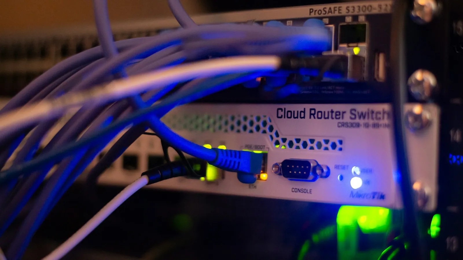 Primer plano de un switch en un rack, con el latiguillado conectado y los pilotos de enlace encendidos